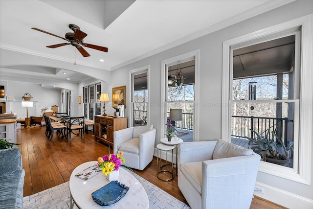 living room with crown molding, wood-type flooring, and ceiling fan