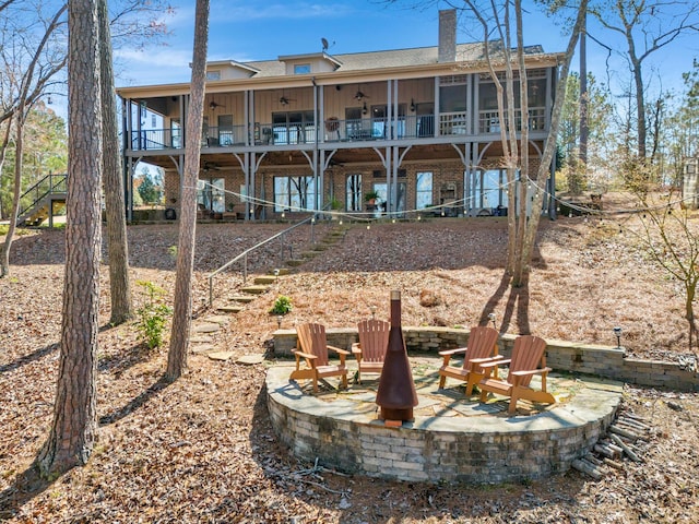 rear view of property featuring a fire pit, a sunroom, and a patio