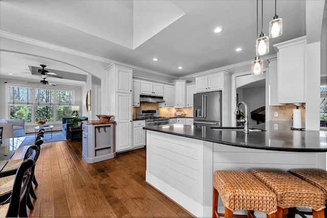 kitchen featuring sink, white cabinetry, stainless steel appliances, dark hardwood / wood-style floors, and ornamental molding