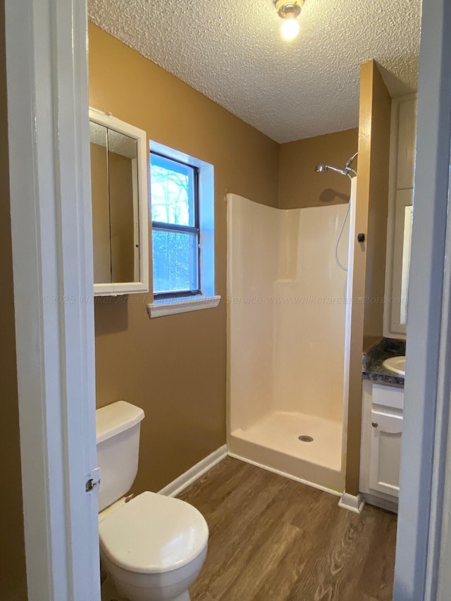 full bath with a textured ceiling, vanity, walk in shower, and wood finished floors