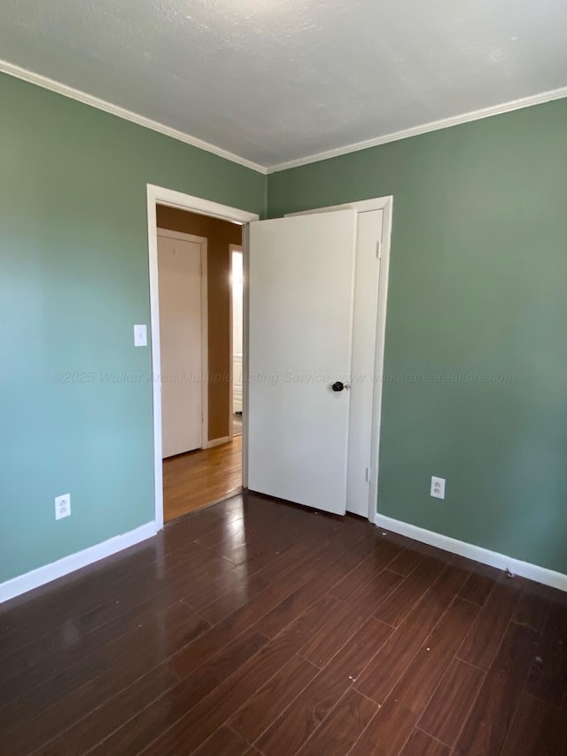 empty room with ornamental molding, baseboards, and wood finished floors