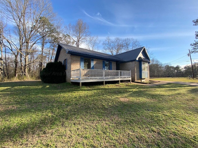 view of front of property with a deck, a front yard, brick siding, and metal roof