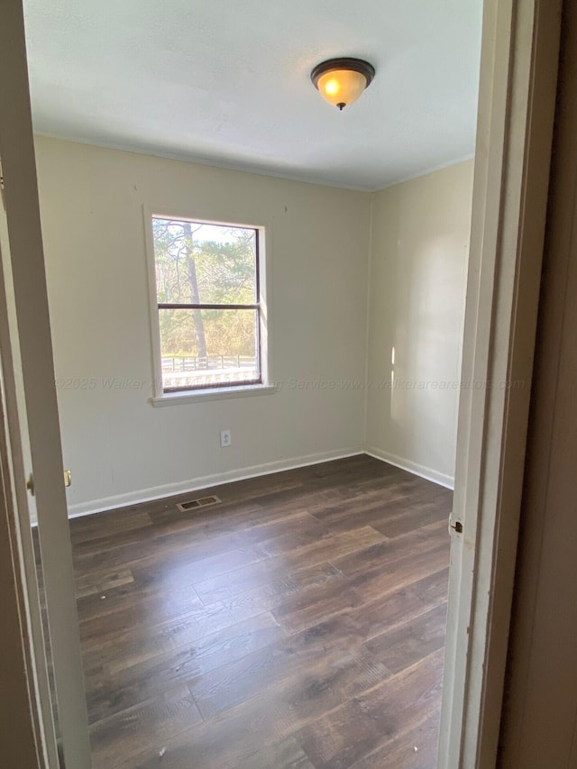 unfurnished room featuring visible vents, baseboards, and dark wood-style flooring