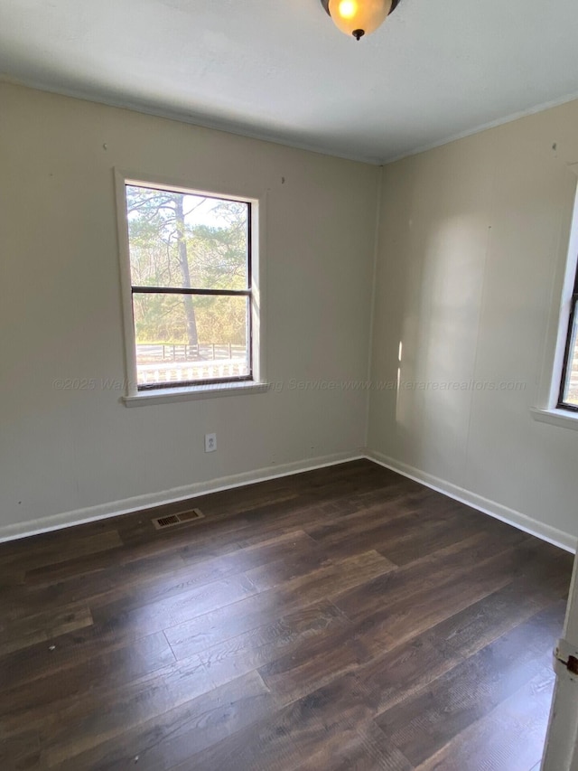 unfurnished room with visible vents, baseboards, and dark wood-type flooring