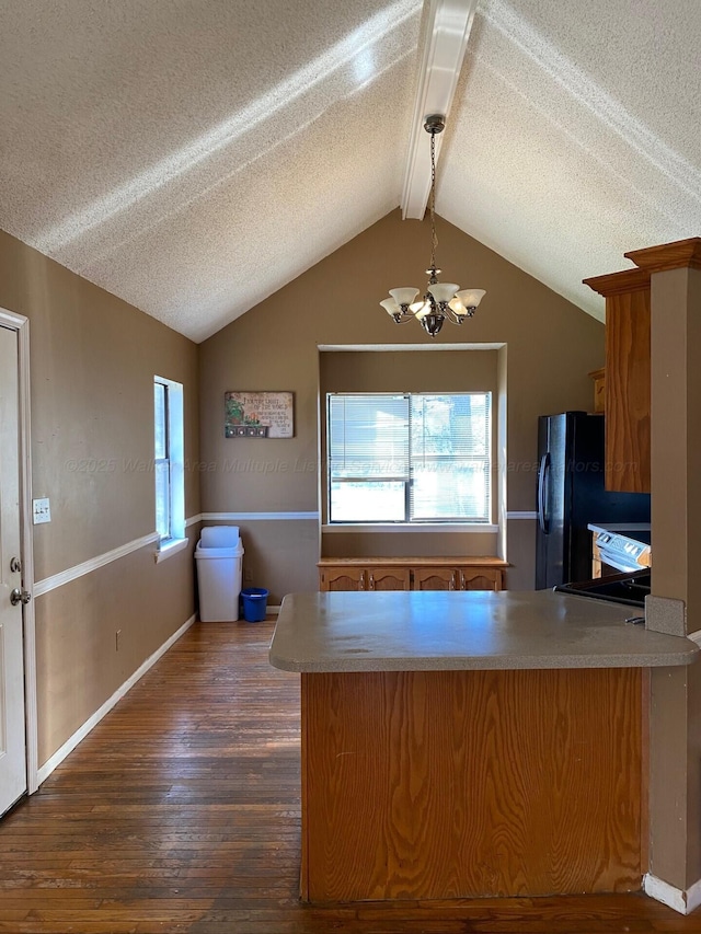 kitchen with dark wood-style floors, lofted ceiling with beams, freestanding refrigerator, and a peninsula