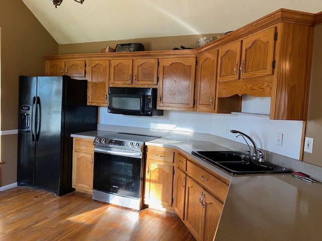 kitchen featuring a sink, brown cabinets, light wood-style floors, and black appliances