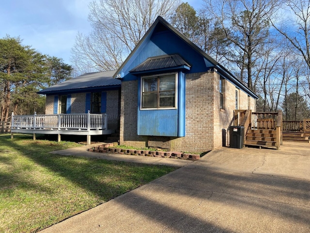 view of front of home with brick siding, a wooden deck, a front yard, and metal roof