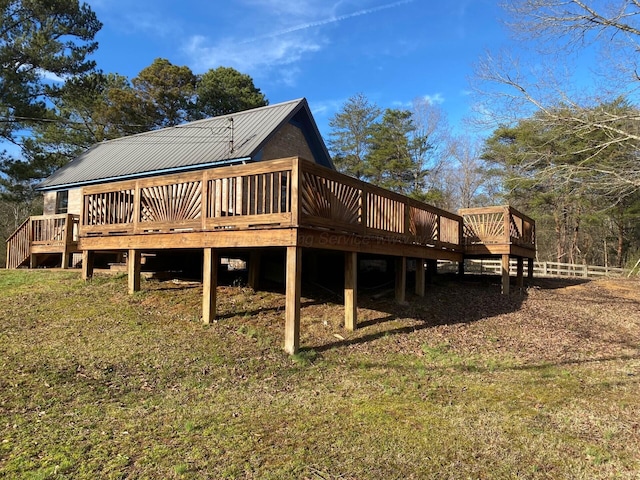 rear view of property featuring metal roof, a wooden deck, and fence