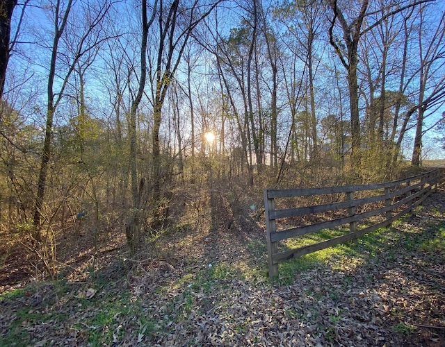 view of gate featuring a view of trees and fence