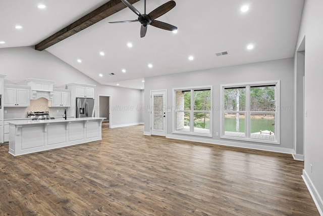 unfurnished living room featuring ceiling fan, dark wood-type flooring, high vaulted ceiling, and beamed ceiling