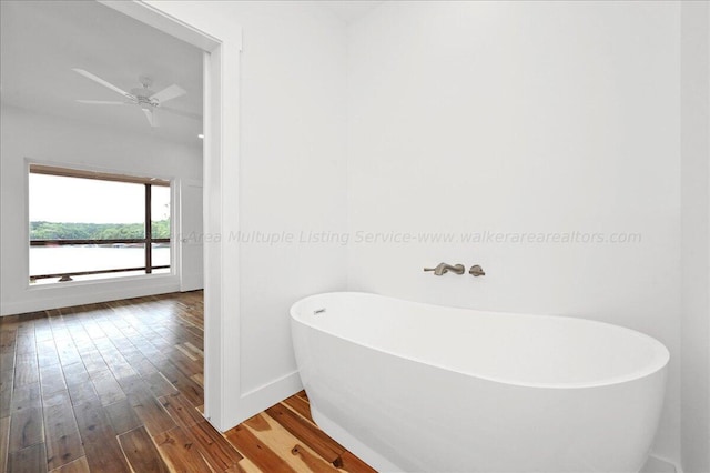 bathroom with ceiling fan, a bath, and hardwood / wood-style flooring