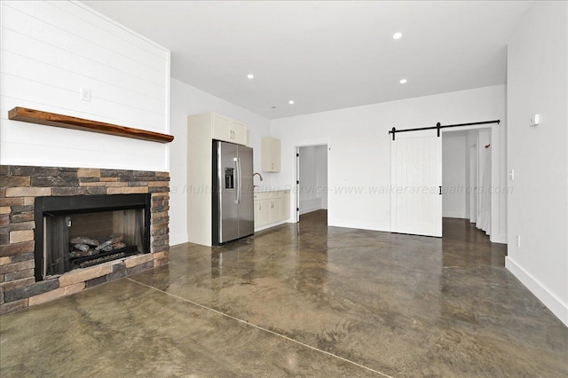 unfurnished living room featuring a fireplace and a barn door