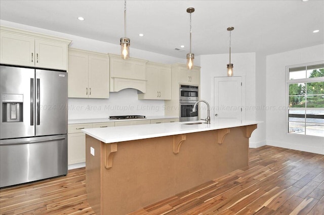 kitchen featuring cream cabinetry, stainless steel appliances, and an island with sink