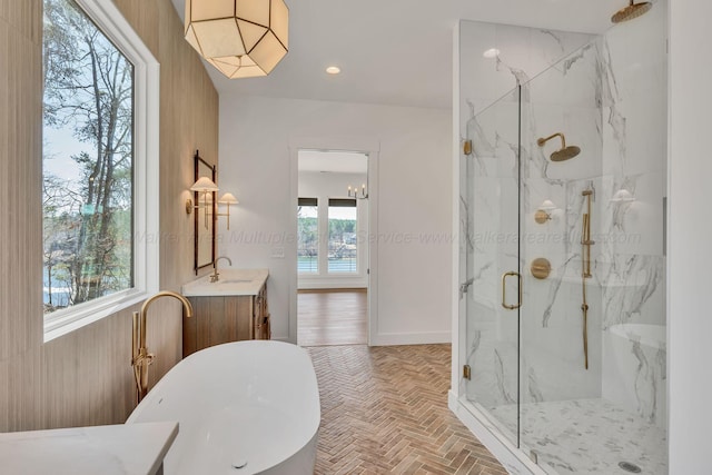 full bathroom featuring brick floor, a marble finish shower, a soaking tub, vanity, and baseboards