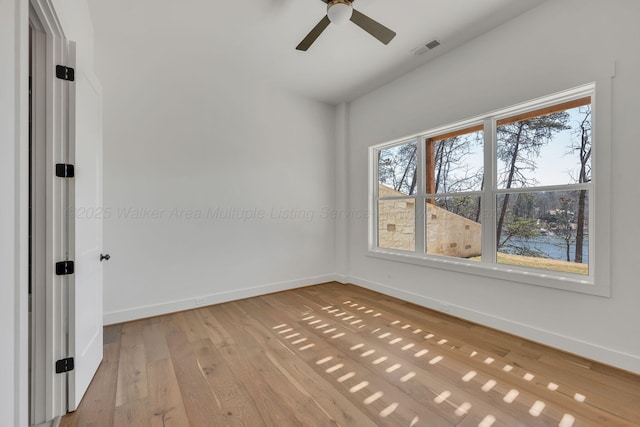 unfurnished room featuring light wood finished floors, a ceiling fan, visible vents, and baseboards