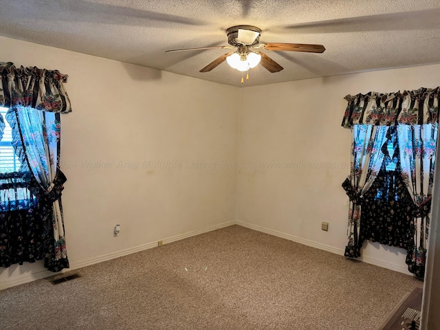 carpeted spare room featuring ceiling fan and a textured ceiling