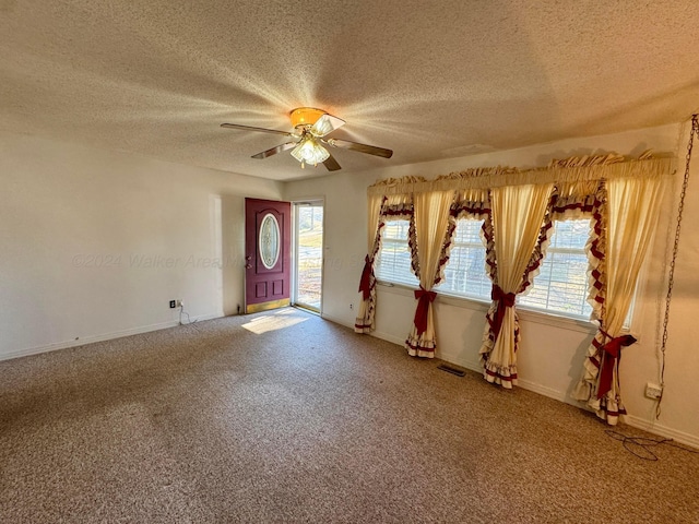 carpeted foyer entrance featuring ceiling fan and a textured ceiling