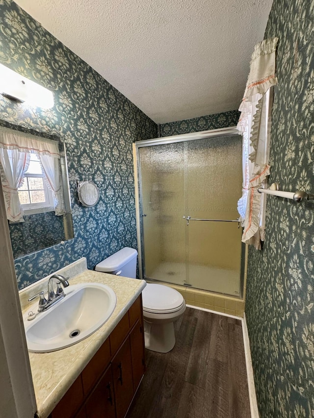 bathroom with an enclosed shower, vanity, a textured ceiling, hardwood / wood-style flooring, and toilet