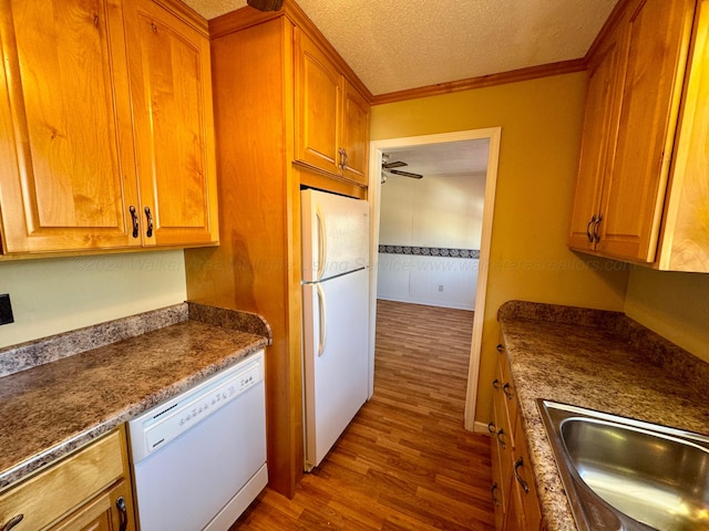 kitchen with sink, hardwood / wood-style floors, a textured ceiling, white appliances, and ornamental molding