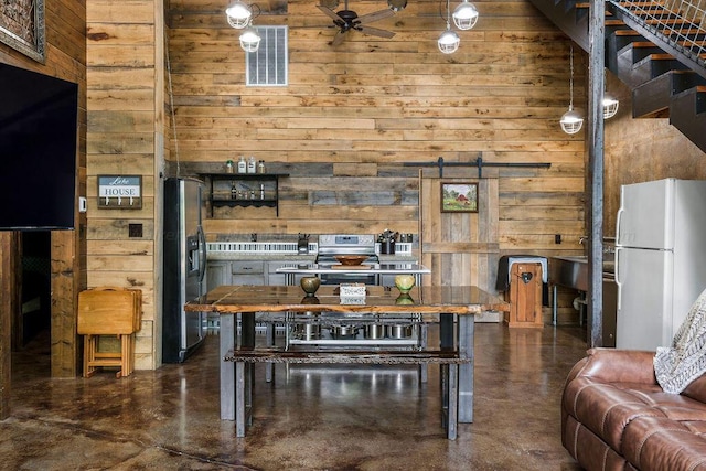 dining area featuring wood walls, a barn door, concrete flooring, and a high ceiling