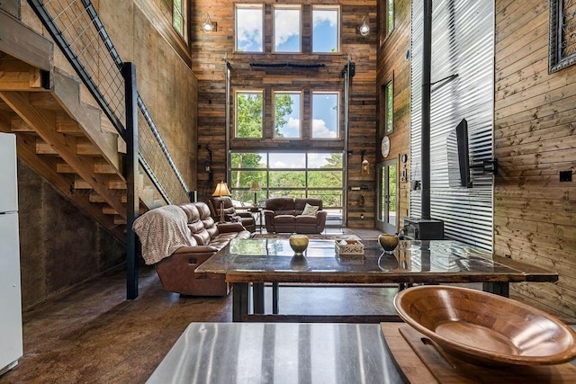 living area featuring a towering ceiling, wooden walls, and a wood stove