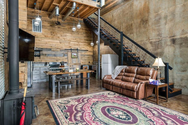 living room featuring beam ceiling, a towering ceiling, a barn door, and wooden ceiling