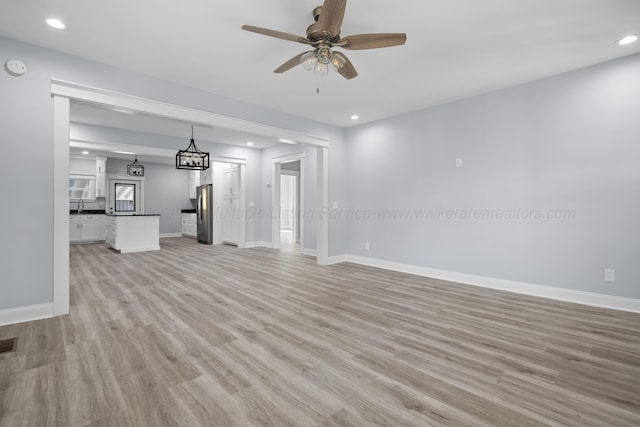 unfurnished living room featuring ceiling fan and light hardwood / wood-style floors