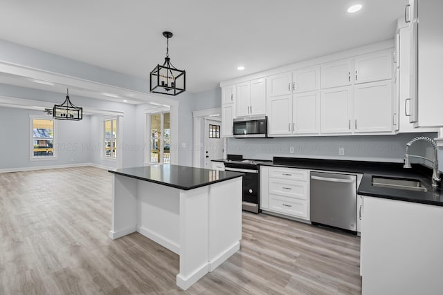 kitchen featuring a kitchen island, appliances with stainless steel finishes, pendant lighting, white cabinetry, and sink