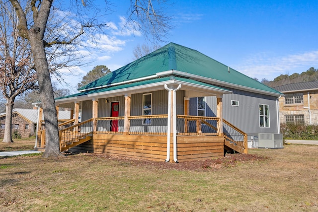 view of front of property with cooling unit, covered porch, and a front yard