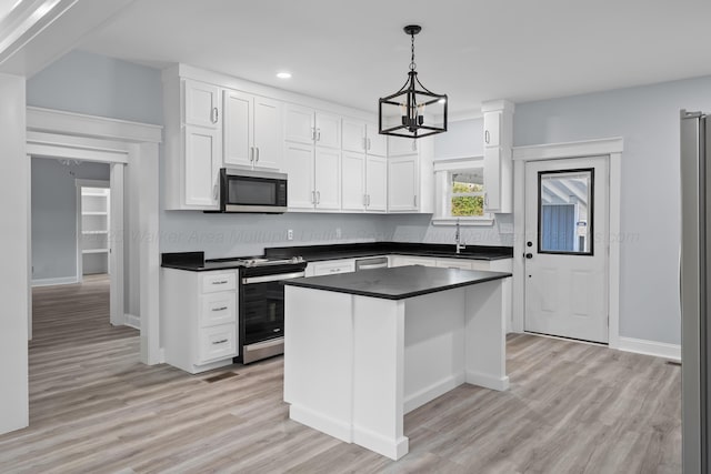 kitchen featuring a kitchen island, appliances with stainless steel finishes, pendant lighting, sink, and white cabinets