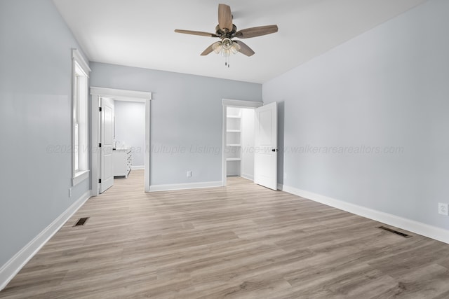 unfurnished bedroom featuring ceiling fan, a spacious closet, and light hardwood / wood-style flooring