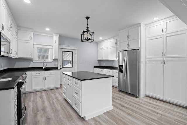 kitchen featuring white cabinetry, decorative light fixtures, light wood-type flooring, and appliances with stainless steel finishes