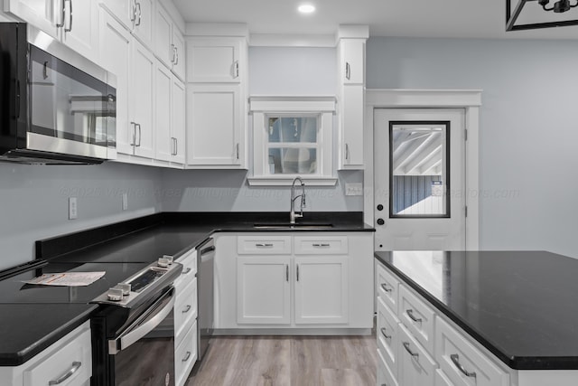 kitchen with white cabinetry, stainless steel appliances, sink, and light wood-type flooring