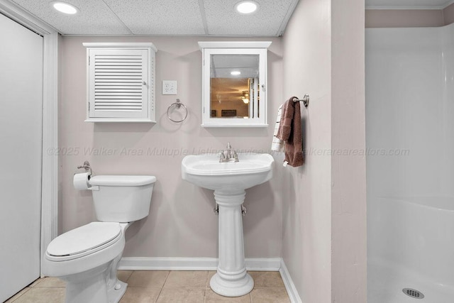 bathroom with toilet, a paneled ceiling, and tile patterned flooring