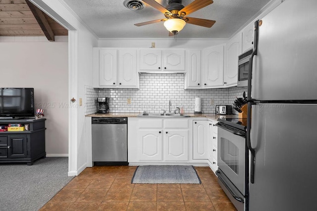 kitchen with dark carpet, ceiling fan, stainless steel appliances, white cabinets, and sink