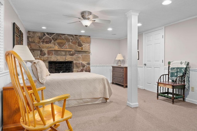 bedroom featuring ceiling fan, carpet floors, ornamental molding, and a stone fireplace