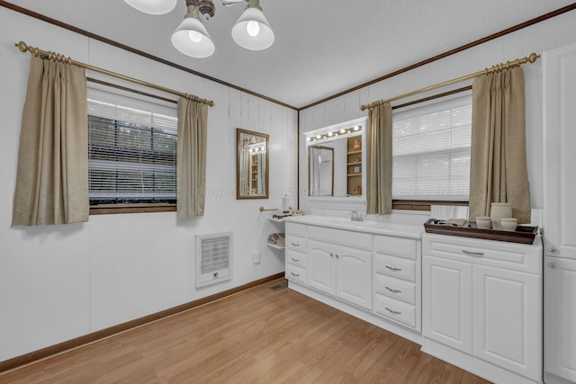 bathroom featuring crown molding, hardwood / wood-style floors, vanity, and a textured ceiling