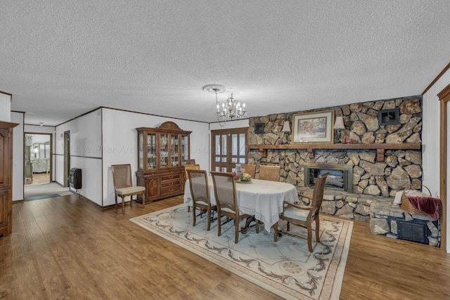 dining area featuring heating unit, a fireplace, wood-type flooring, a notable chandelier, and crown molding