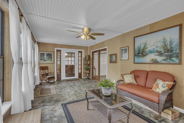 living room with ceiling fan and wood walls