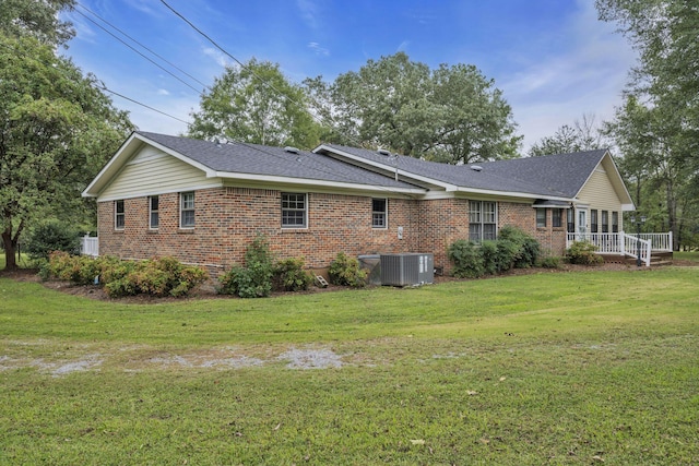 rear view of house featuring central AC and a lawn