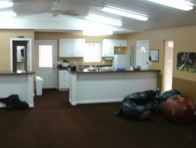 kitchen with vaulted ceiling, white fridge, and white cabinetry