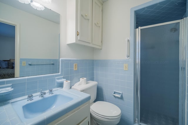 bathroom with vanity, toilet, an enclosed shower, and tile walls