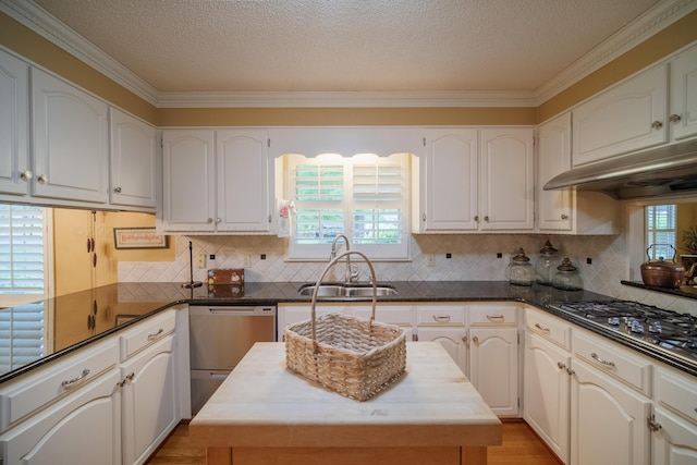 kitchen with a center island, stainless steel appliances, ornamental molding, and sink