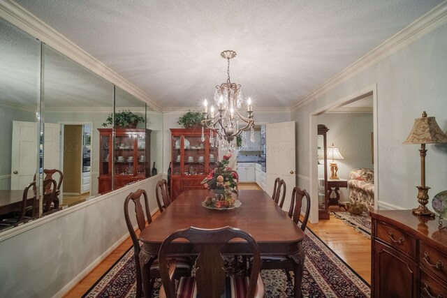 dining room with a chandelier, crown molding, wood-type flooring, and a textured ceiling