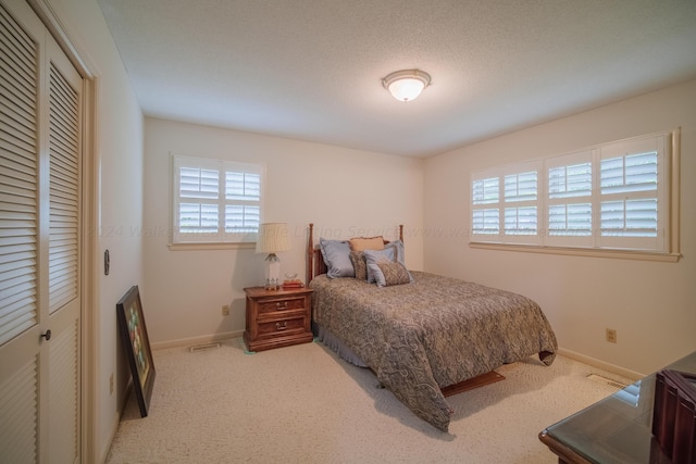 bedroom featuring a textured ceiling and light carpet