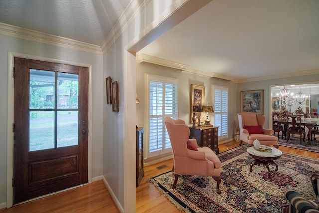 foyer featuring crown molding, light hardwood / wood-style flooring, and a chandelier