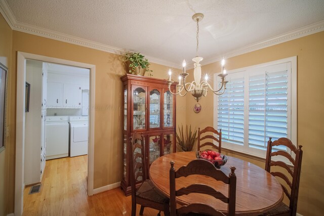 dining space with an inviting chandelier, crown molding, light wood-type flooring, a textured ceiling, and washing machine and clothes dryer