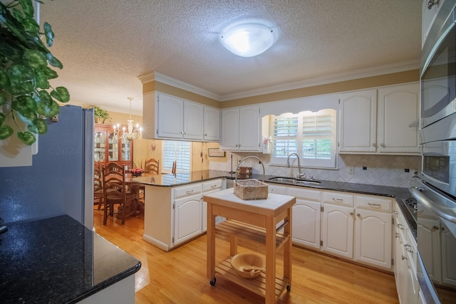 kitchen with white cabinets, crown molding, light wood-type flooring, and sink