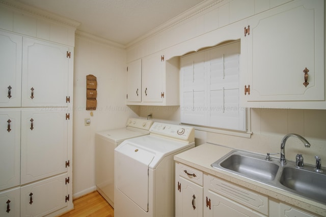 washroom with cabinets, crown molding, sink, separate washer and dryer, and light hardwood / wood-style flooring