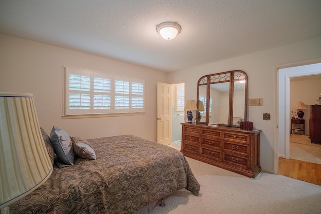 bedroom featuring light colored carpet and a textured ceiling